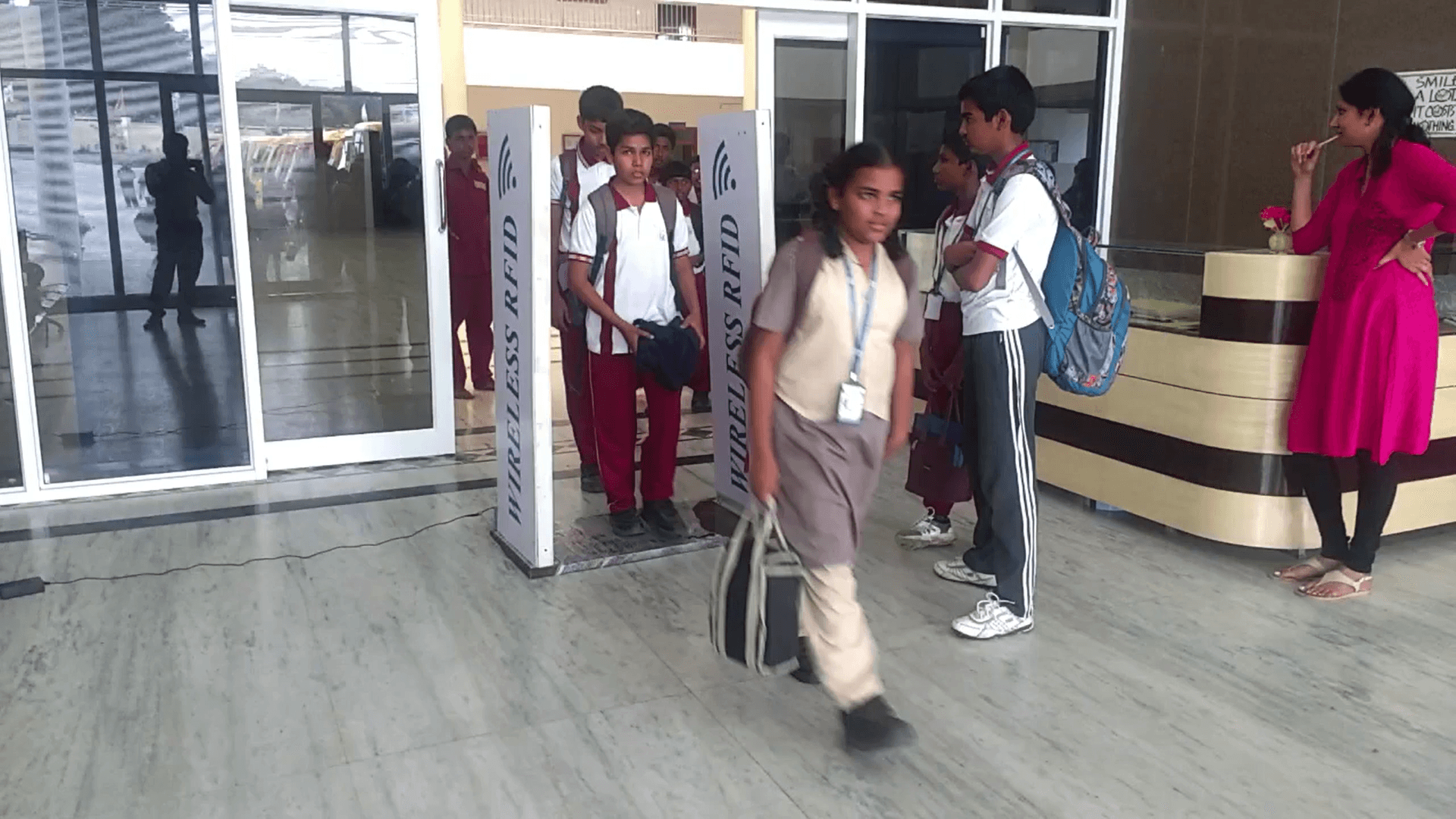 Student walking through a Nepal school gate with SMS alerts.